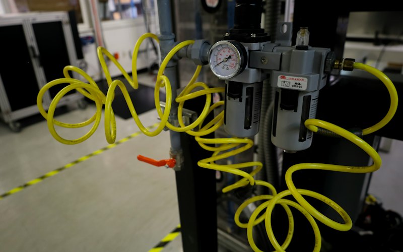 Tuyau souple jaune en spirale raccordé à un filtre-régulateur à manomètre, dans un atelier